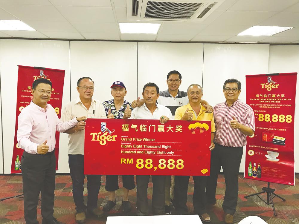 Three lucky grand prize winners receiving their big ang pow from Tiger Malaysia executives ... Teh (C) sharing his fortune with his friends.