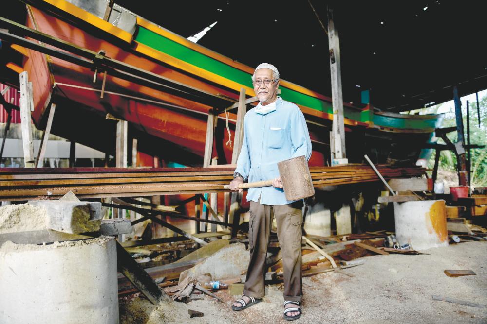 $!Shafie showing one of the implements he uses to make his boats. – Bernamapix