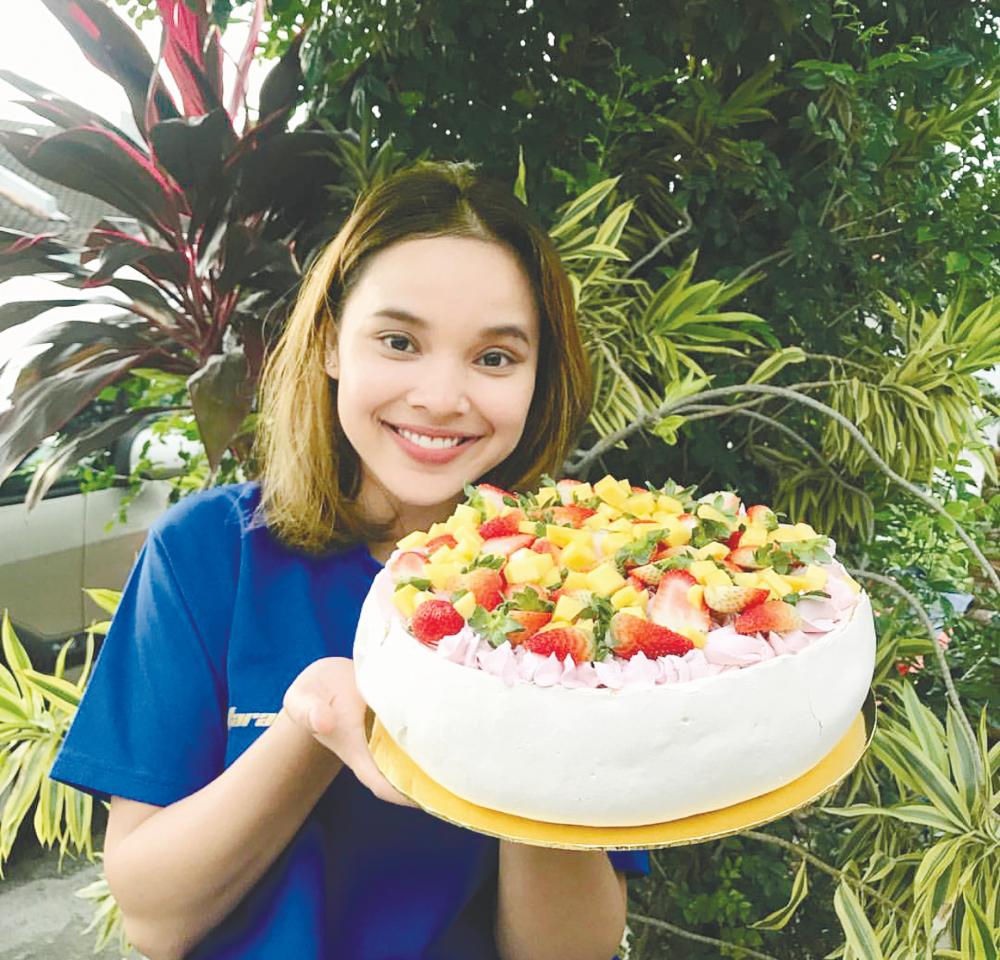 Farah with one of her creations, a large pavlova with strawberry cream and fresh fruits– Courtesy of Farah Azrooein Ghazali