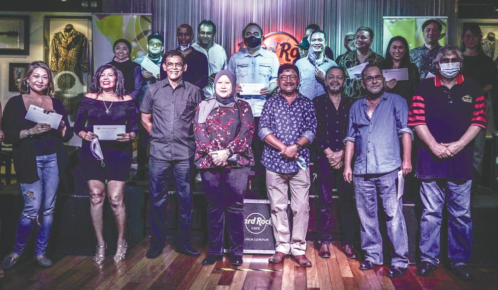Entertainers and Karyawan officials pose for a group picture during a cheque presentation event at Hard Rock Cafe in Kuala Lumpur on Sunday. – AMIRUL SYAFIQ/THESUN