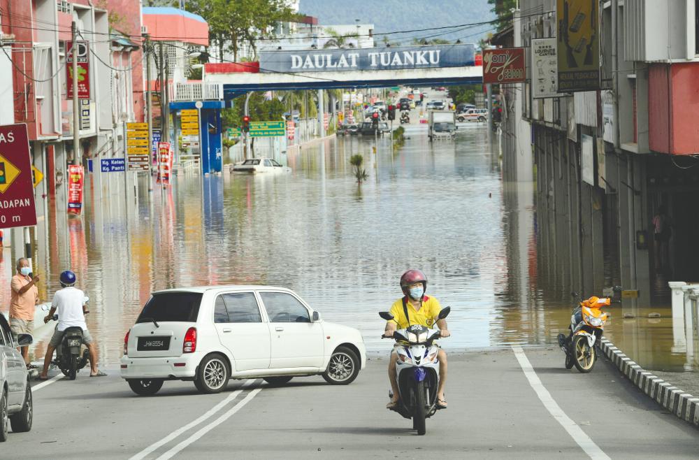 $!Motorists being forced to turn back after they encountered a road that had been cut off by floodwaters in Kota Tinggi, Johor. – BERNAMAPIX