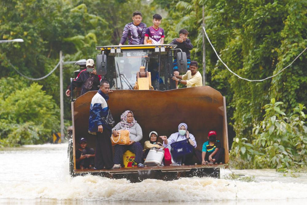 $!UNUSUAL RIDE ... Villagers being evacuated in an excavator through floodwaters following a monsoon downpour in Lanchang, Pahang yesterday. – AFPPIX