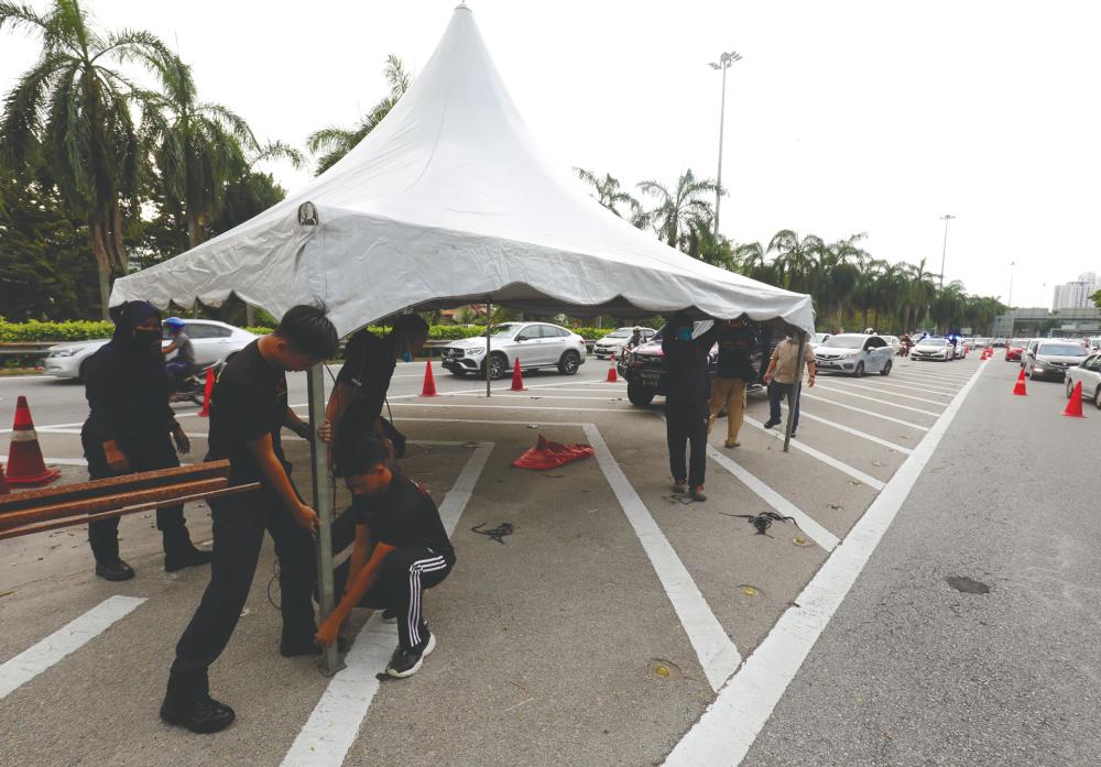 Police personnel setting up a checkpoint at the Tun Dr Lim Chong Eu Highway leading to the Penang Bridge in George Town yesterday, ahead of a movement control order that comes into effect today. – MASRY CHE ANI/THESUN