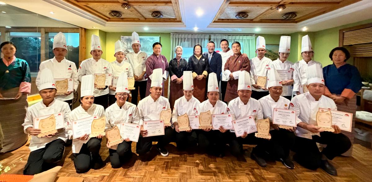 Zimpon Wom Sonam Thinley, Steering Committee Member, Desuung Skilling Programme (back row, sixth from left), Dasho Tashi Wangmo, Secretary of the Ministry of Industry, Commerce and Employment, Royal Government of Bhutan (back row, seventh from left), Dasho Kesang Chuki Dorjee, Eminent Member, National Council of Bhutan, Steering Committee Member, Desuung Skilling Programme (back row, eighth from right), Karma Tshering, Executive Director, Post Skilling, Steering Committee Member, Desuung Skilling Programme (back row, fifth from right), Dodie Hung, Executive Vice President – Corporate Affairs of Lee Kum Kee Sauce (back row, seventh from right), and Chef Vincent Liew, Executive Chef at The Star Sydney (back row, sixth from right), present certificates to young chefs of the culinary culture exchange programme.