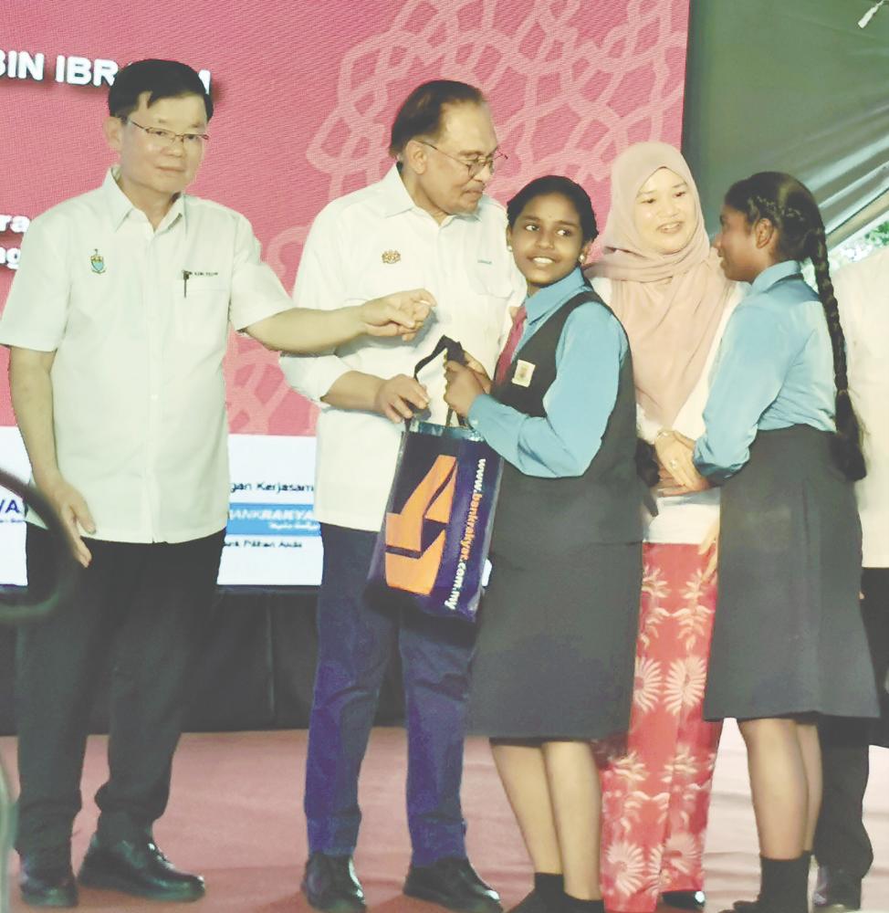 Anwar and Chow presenting the aid items to recipients at the event. – T.C. Khor/ theSun