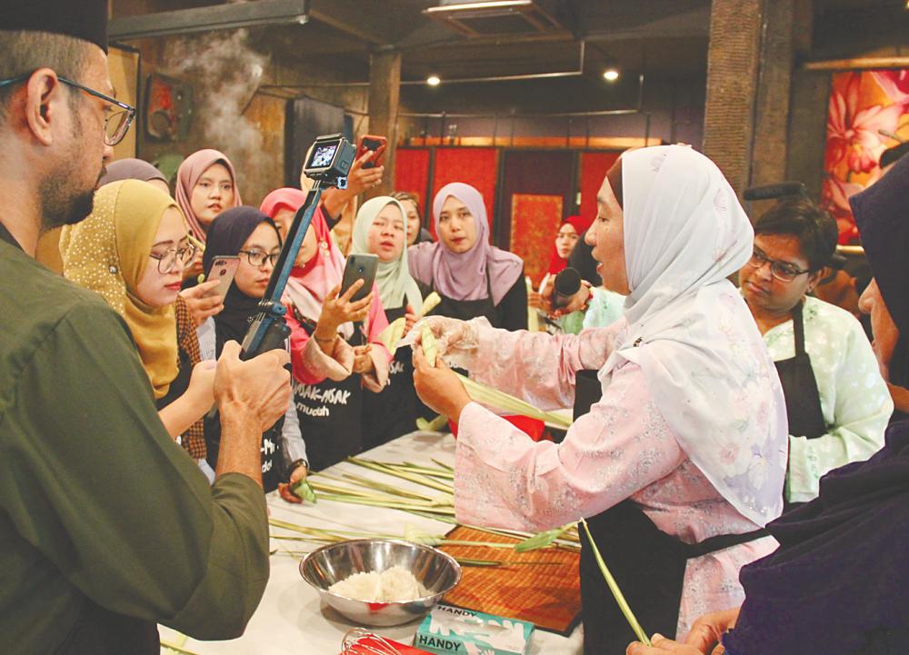 Kak Iza demonstrating how to make ketupat palas.