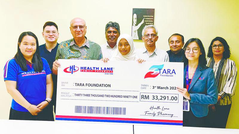 Pardip (third left) receives a mock cheque for RM33,291 on behalf of Tara Foundation from Yan (second right) of Health Lane Family Pharmacy.