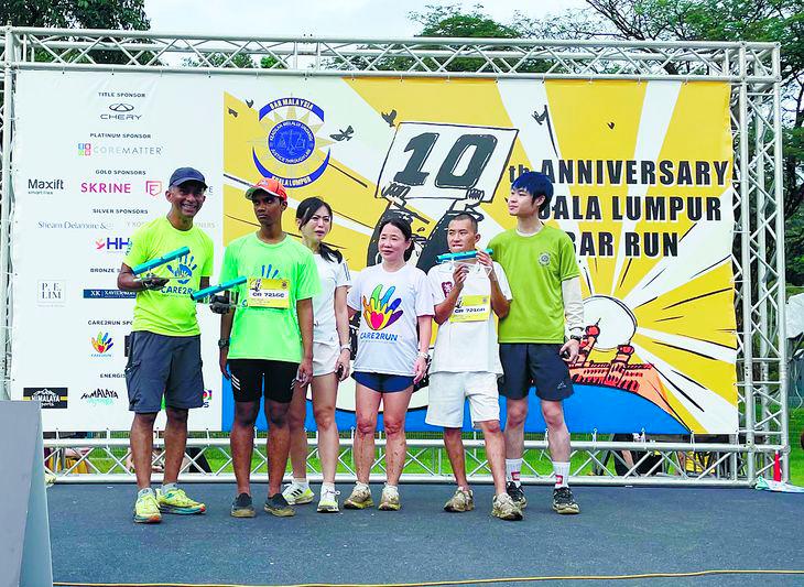 (left) Prem handing out prizes won by SN adults in the presence of Tan Lay Geok (fourth left), one of the founders of Care2Run and a lawyer by profession, with volunteer participants.
