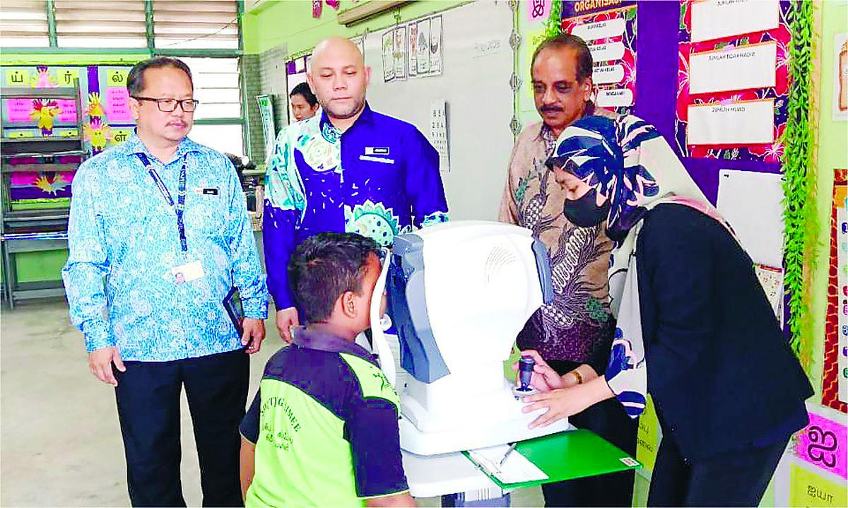 Ahmad Maswan (centre) watching a pupil undergoing eye screening.