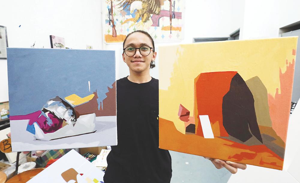 Aleff with two of his completed paintings. – MASRY CHE ANI/THESUN
