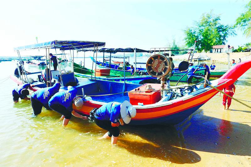 $!Volunteers from Nestle Malaysia and UMT clean barnacles off fishing boats at Pantai Tok Jembal to help improve safety and efficiency, as part of Nestle's 2025 coastal cleanup.