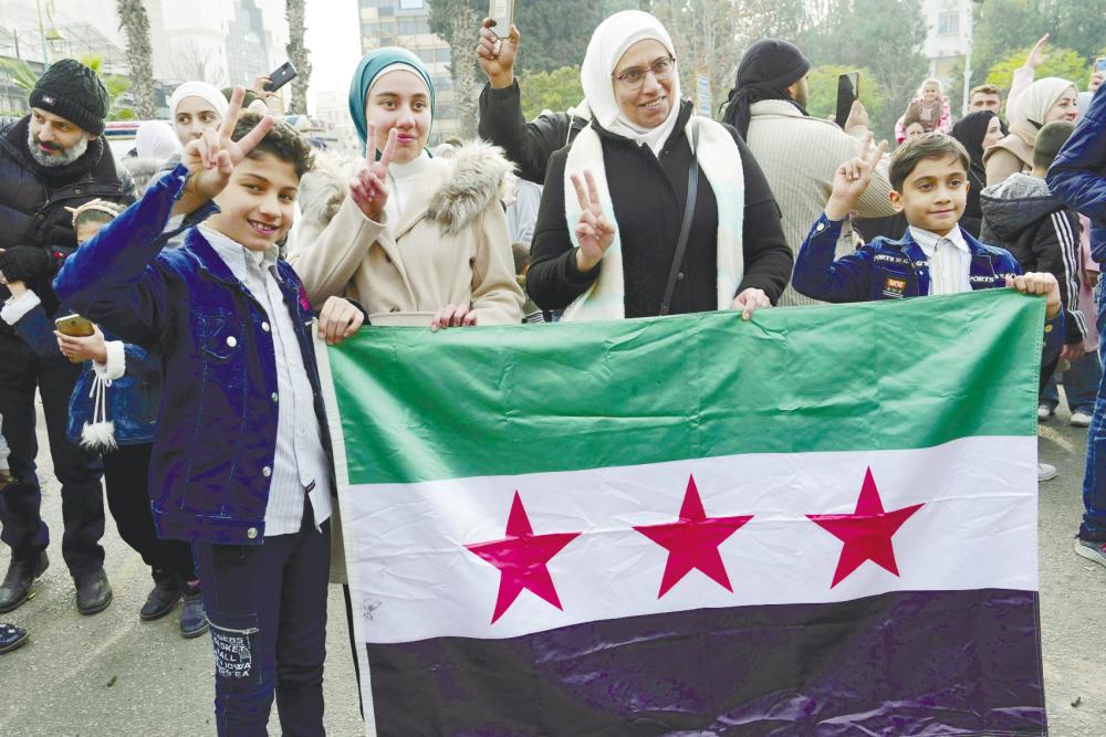 Syrians flash the V for victory sign as they celebrate in the central city of Homs on Monday, after rebel forces entered Syria’s third city overnight. – AFPPIC