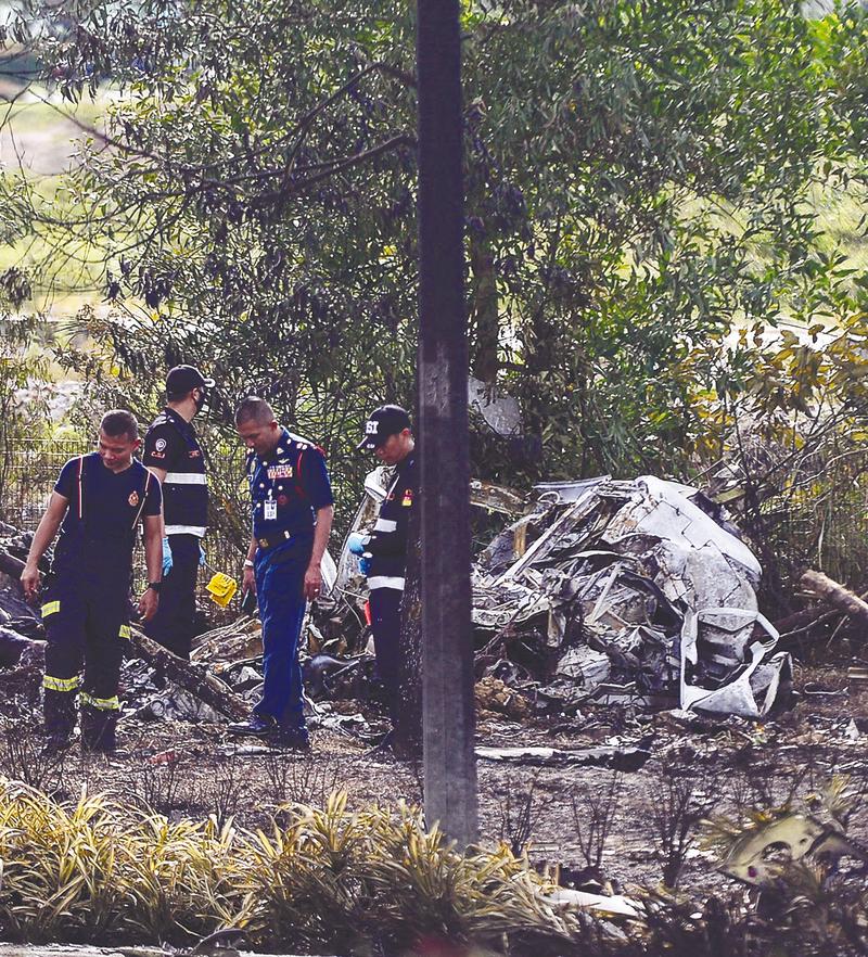 $!Firefighters and aviation officials examining part of the wreckage. – ADIB RAWI YAHYA/THESUN