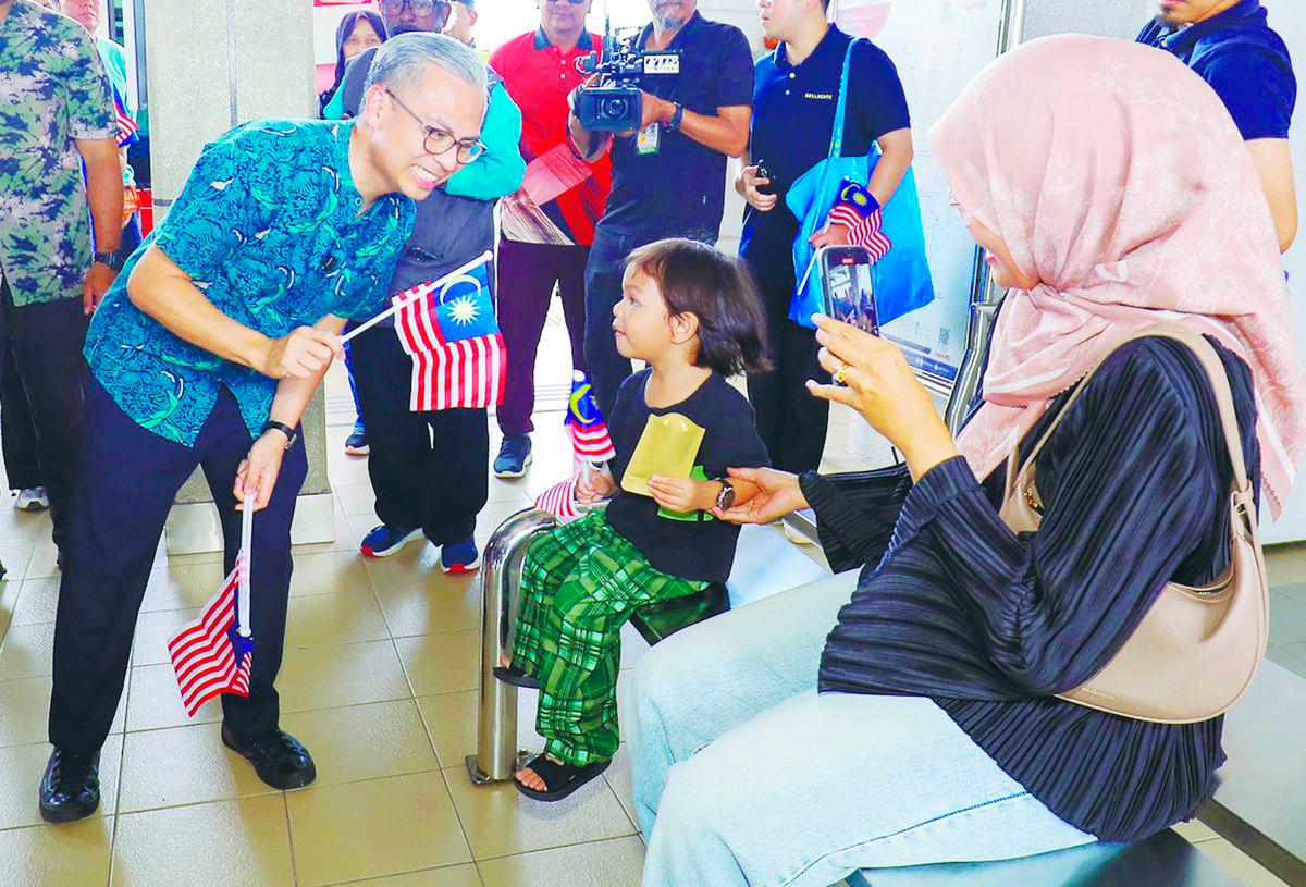 Fahmi waving the national flag with visitors at the launch event yesterday. – Adib Rawi Yahya/theSun