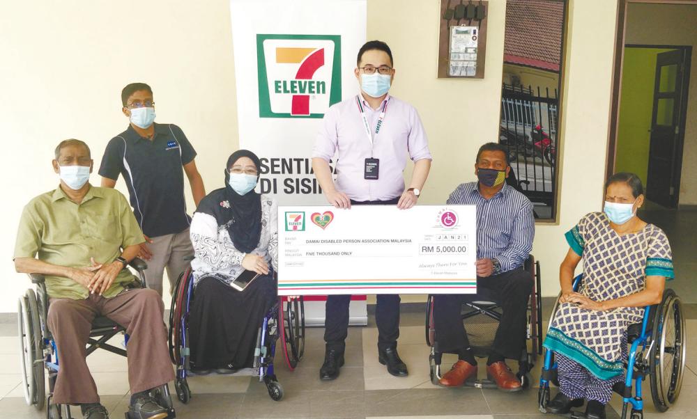 7-Eleven Malaysia’s representative (centre) presenting a mock cheque to Murugeswaran (second from right) alongside its committee members.