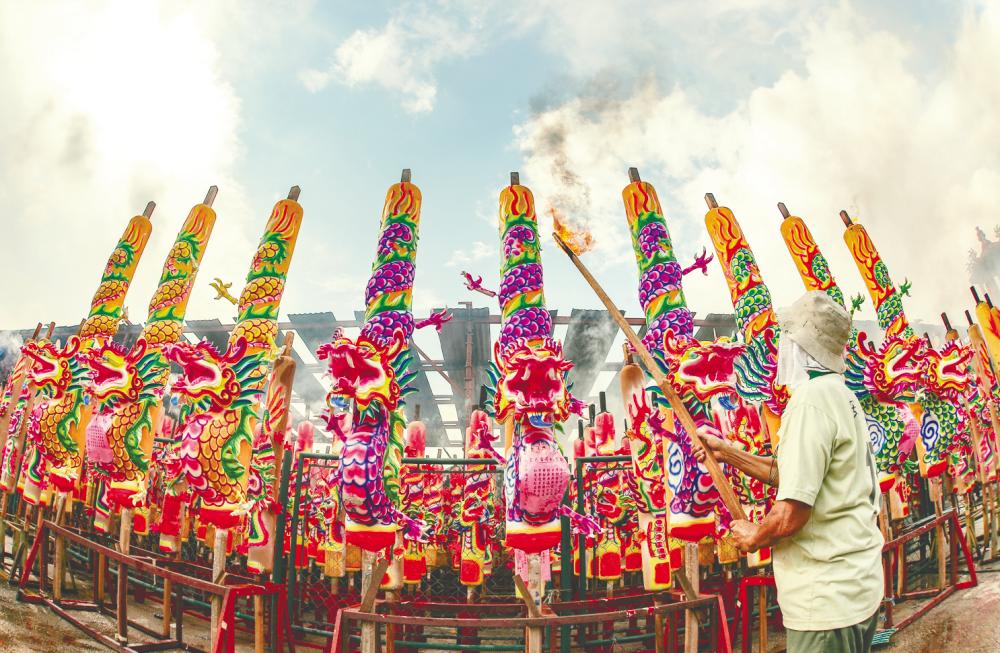 A temple worker in Ampang lights giant joss sticks to prepare for The Nine Emperor Gods Festival in Kuala Lumpur on Oct 8, 2018. — Sunpix by Amirul Syafiq Mohd Din