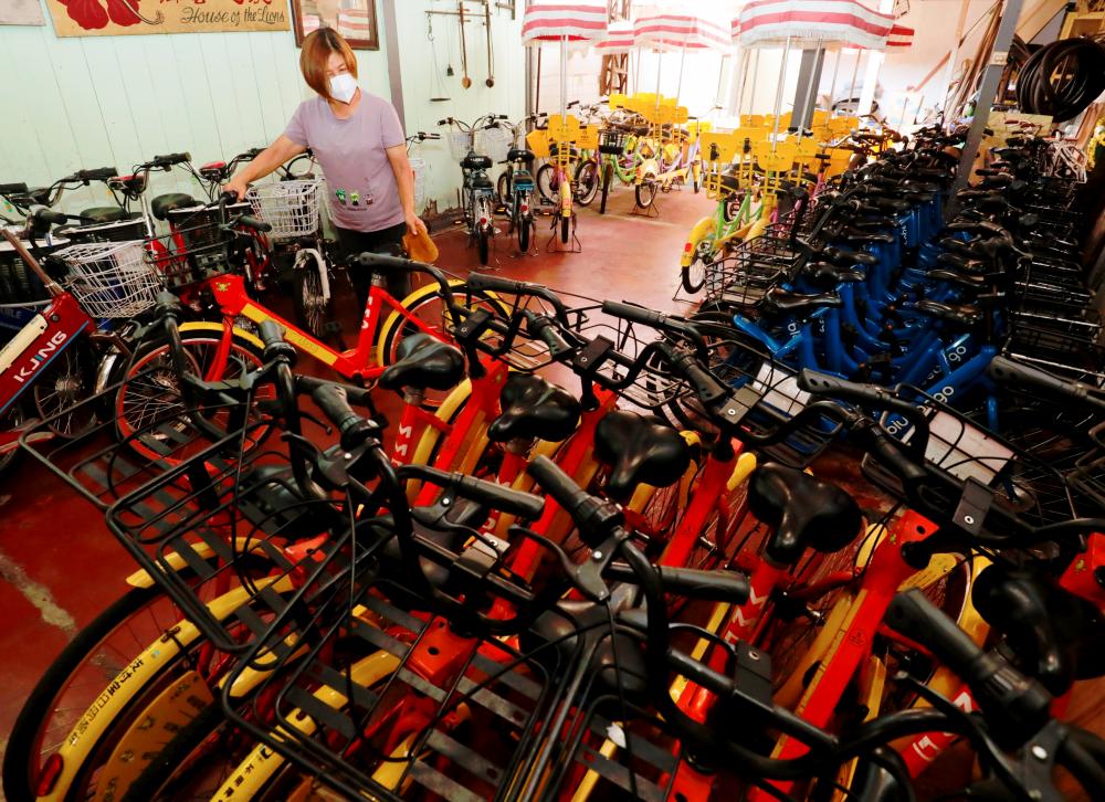 $!NO TAKERS ... Rent-a-bike shop assistant Tan Suan Gaik cleans bicycles that have been left gathering dust at her shop in Lebuh Armenian, George Town, yesterday. Bicycle rental business in the city has been hard hit by the movement control order. – MASRY CHE ANI/THESUN