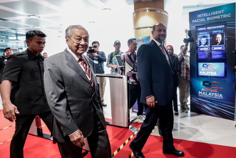 Prime Minister Tun Dr Mahathir Mohamad and Communications and Multimedia Minister Gobind Singh Deo pass the “intelligent facial biometric” path at the launching of the 5G Malaysia showcase in Putrajaya on April 18, 2019. — Sunpix by Ashraf Shamsul