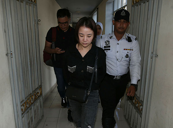 Liu Shasha, 25, accompanied by police at the Majistrates Court in Georgetown today. — Sunpix by Masry Che Ani