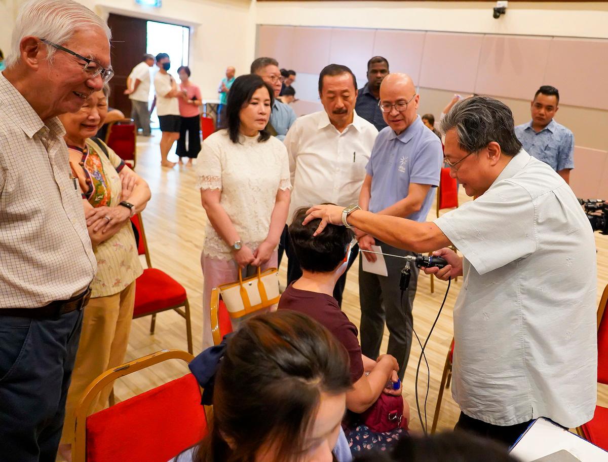 Tan (centre) and his wife Puan Sri Esther and Chin watching a volunteer doctor examine a participant during the event. – AMIRUL SYAFIQ/THESUN