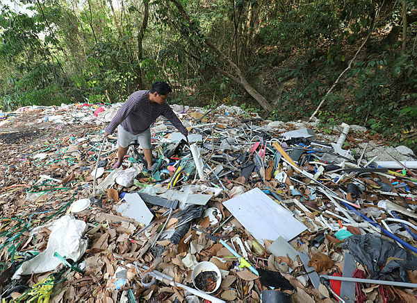 A worker shows waste produced from recycling near a recycling factory in Relau today. — Sunpix by Masry Che Ani