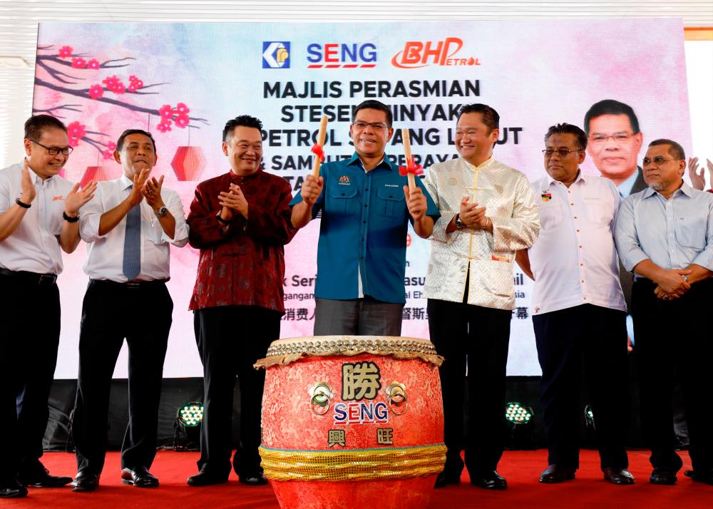 Saifuddin (middle) beating a Chinese drum to mark the BHPetrol outlet’s official opening.