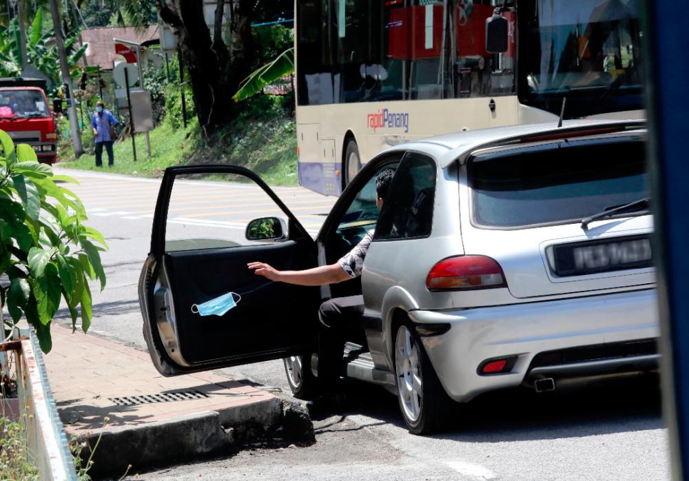 $!A passenger throws a face mask out of the car in blatant disregard for hygiene and cleanliness in a suburb in George Town yesterday. – MASRY CHE ANI/THESUN