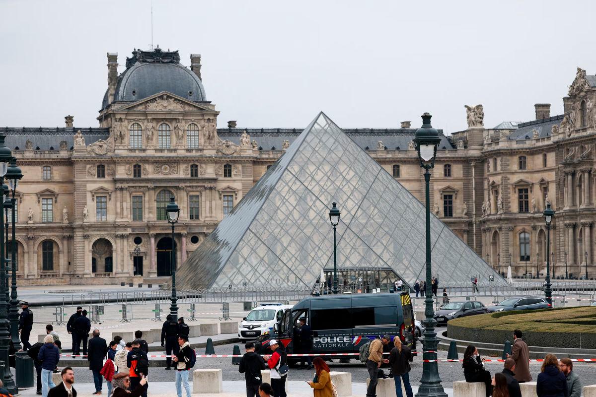 Police stand near the pyramid of the Louvre museum after reports of a robbery, in Paris, France, October 19, 2025. REUTERS/Gonzalo Fuentes