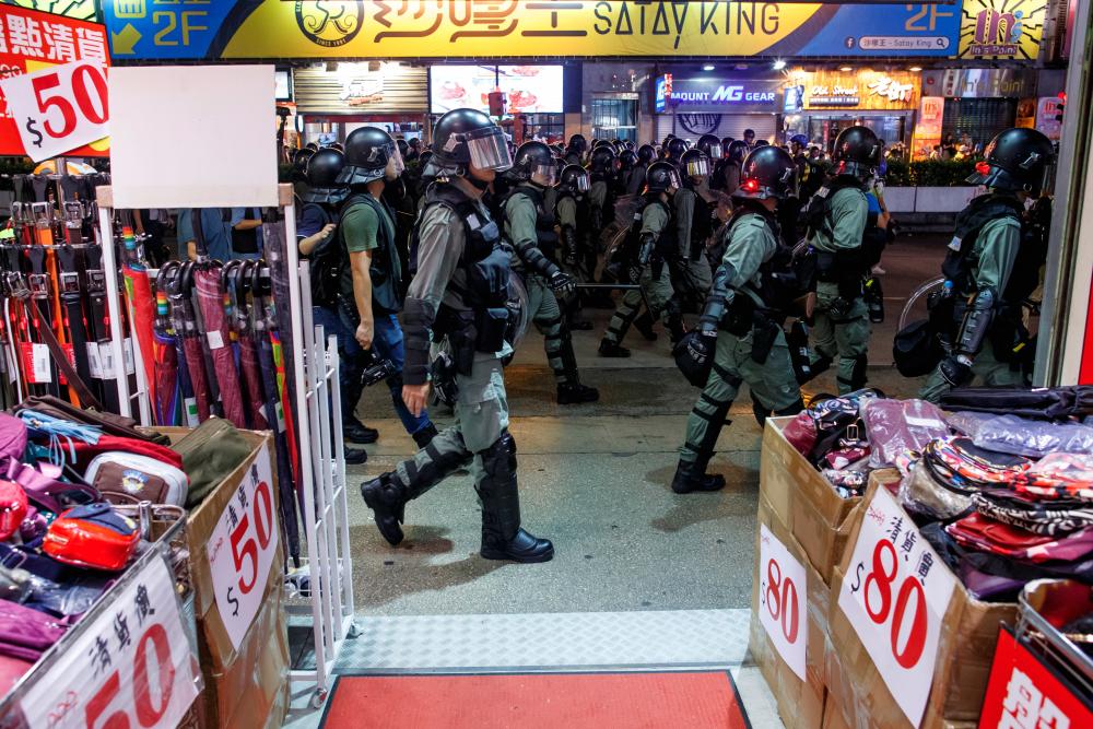 Riot police walk past a shop as they chase anti-government protesters down Nathan Road in Mong Kok in Hong Kong, China August 17, 2019. - Reuters