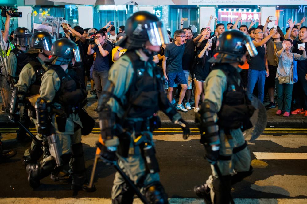Locals shout at riot police as they chase anti-government protesters down Nathan Road in Mong Kok in Hong Kong, China August 17, 2019. - Reuters