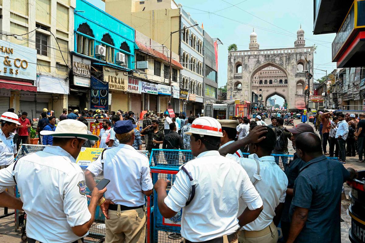 Fire personnel and police stand outside the Krishna Pearls building (blue-colored) that caught fire in Hyderabad on May 18, 2025. AFPpix