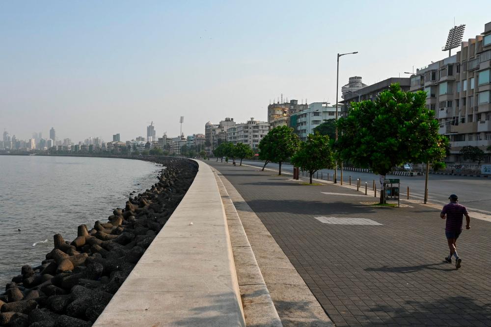 A man runs along the deserted promenade on Marine Drive during a weekend lockdown imposed by the state government amidst rising Covid-19 coronavirus cases in Mumbai on April 10, 2021. — AFP