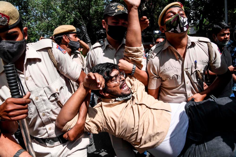 A protestor (C) shouts slogans while being detained by police during a demonstration outside the Uttar Pradesh Bhawan (state house) in New Delhi on September 30, 2020, a day after a 19-year-old woman who was allegedly gang-raped died from her injuries near Bool Garhi village in the UP state. — AFP