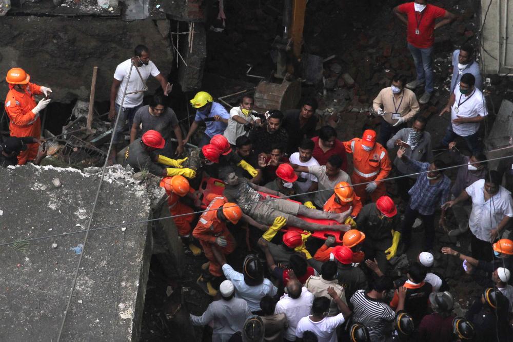 Rescue workers carry a survivor from the rubble of a collapsed three-storey residential building in Bhiwandi on Sept 21, 2020. — AFP