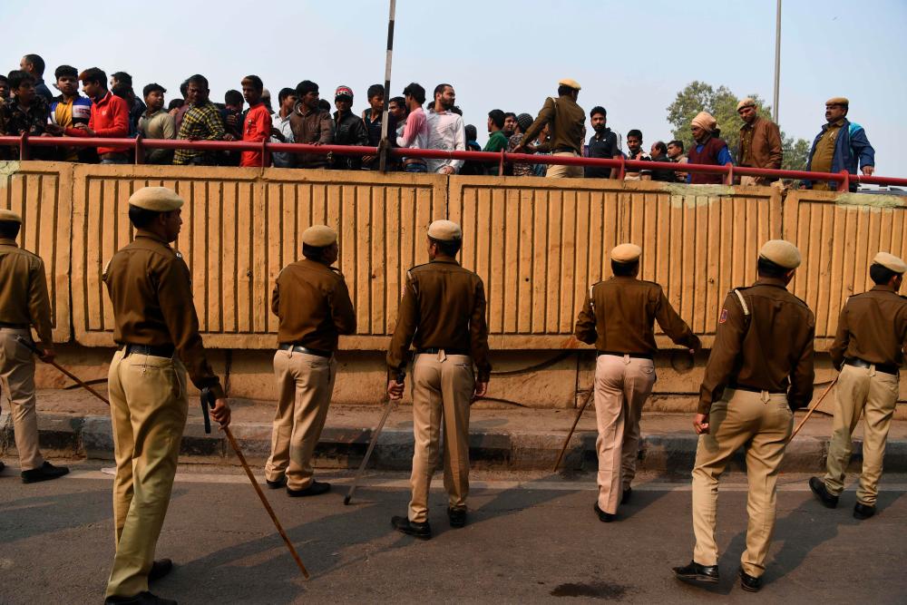 Police personnel move onlookers from a road after following a factory fire in Anaj Mandi area of New Delhi on Dec 8, 2019. — AFP