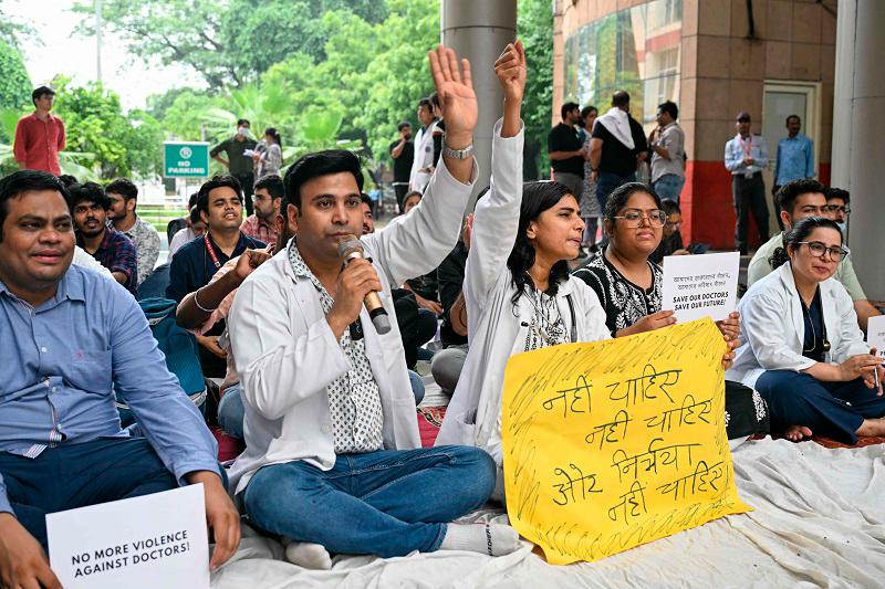 Practicing doctors and medical staff display placards as they take part in a protest against the incident of rape and murder of a young medic in Kolkata, during a demonstration held at a government hospital in New Delhi on August 12, 2024. Indian doctors in government hospitals across several states halted elective services “indefinitely” on August 12 to protest the rape and murder of a young medic. - (Photo by Money SHARMA / AFP)