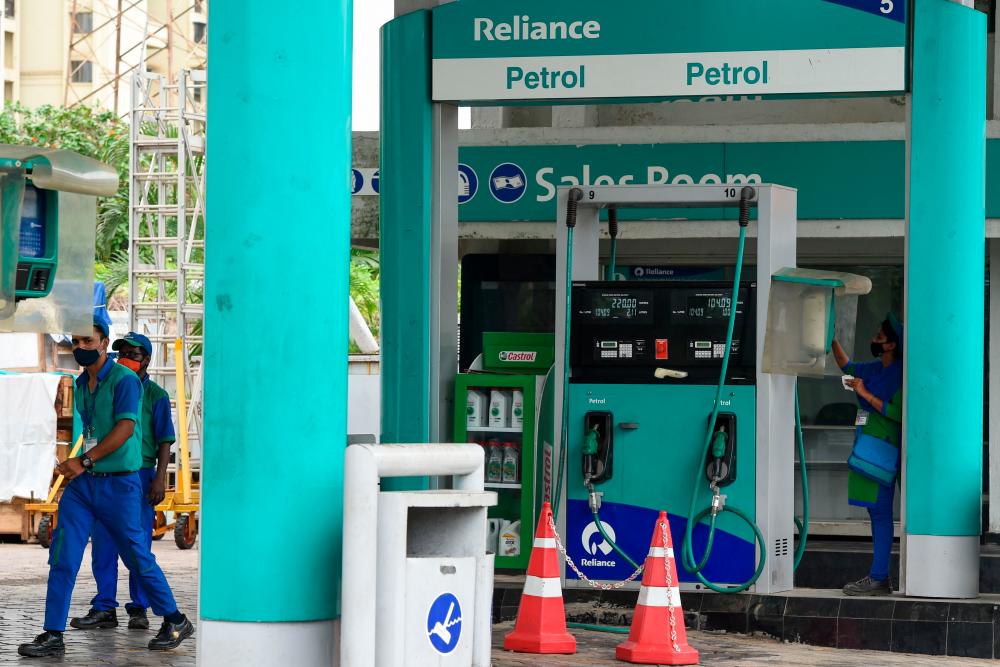 Employees at the Reliance Industries petrol pump in Navi Mumbai on Thursday. The conglomerate's multi-billion-dollar fortune is powered by oil and petrochemicals businesses, but Reliance has aggressively diversified into areas including telecoms and retail in recent years. – AFPPIX