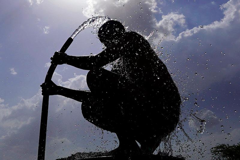 A man is silhouetted against the sun as he bathes on a hot summer day at a village on the outskirts of Ajmer on June 11, 2024 amid heatwave. India's heatwave is the longest ever to hit the country, the government's top weather expert said on June 10 as he warned people will face increasingly oppressive temperatures. Parts of northern India have been gripped by a heatwave since mid-May, with temperatures soaring over 45 degrees Celsius (113 degrees Fahrenheit). - Himanshu SHARMA / AFP