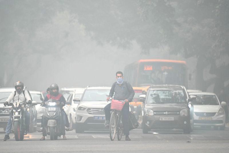 A cyclist with his face covered in cloth rides along a street on a cold smoggy morning in New Delhi - AFPpix