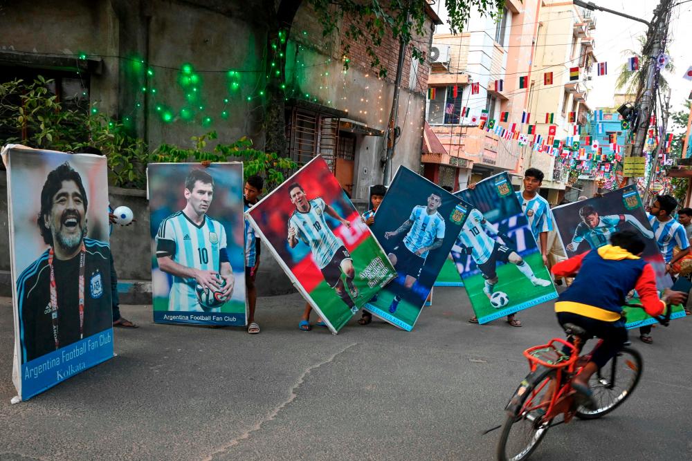 $!Football fans carry posters of Argentina team players to celebrate the Qatar 2022 FIFA World Cup football tournament, along a street in Kolkata. – AFPPIX
