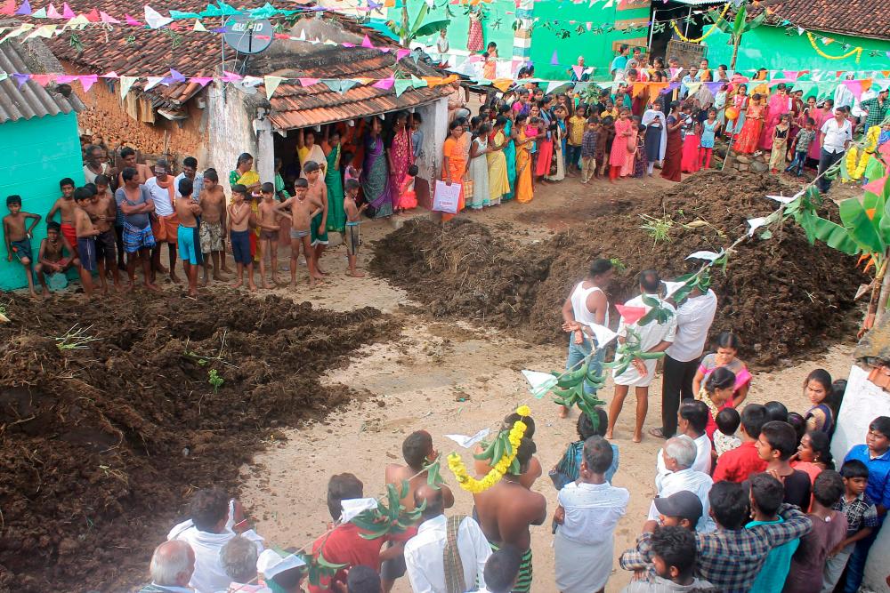 $!In this picture taken on November 17, 2020 people stand beside heaps of cow dung during the “Gorehabba” festival at Gumatapura village on the border of India’s Karnataka and Tamil Nadu states. AFP / Padmanabha RAO