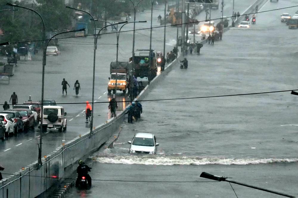 Commuters make their way through a flooded road after heavy rains in Chennai on December 4, 2023. Cyclone Michuang is expected to make landfall on December 5 along the southern coast/AFPPix