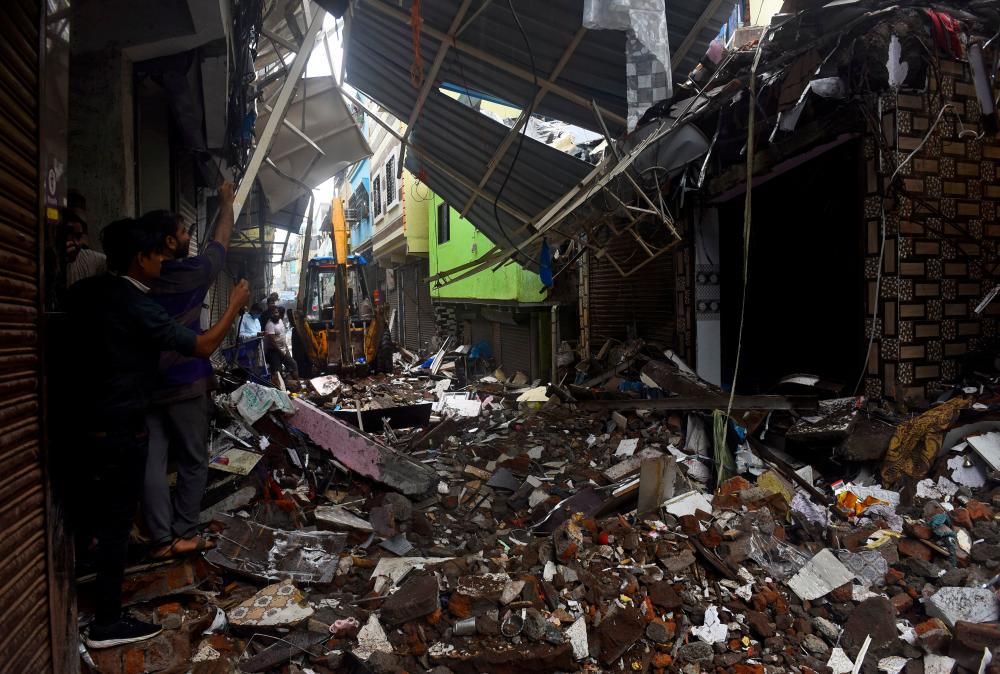 People use their mobile phones to take pictures of a collapsed building following rains in Mumbai, India, July 23, 2021. — Reuters/Stringer
