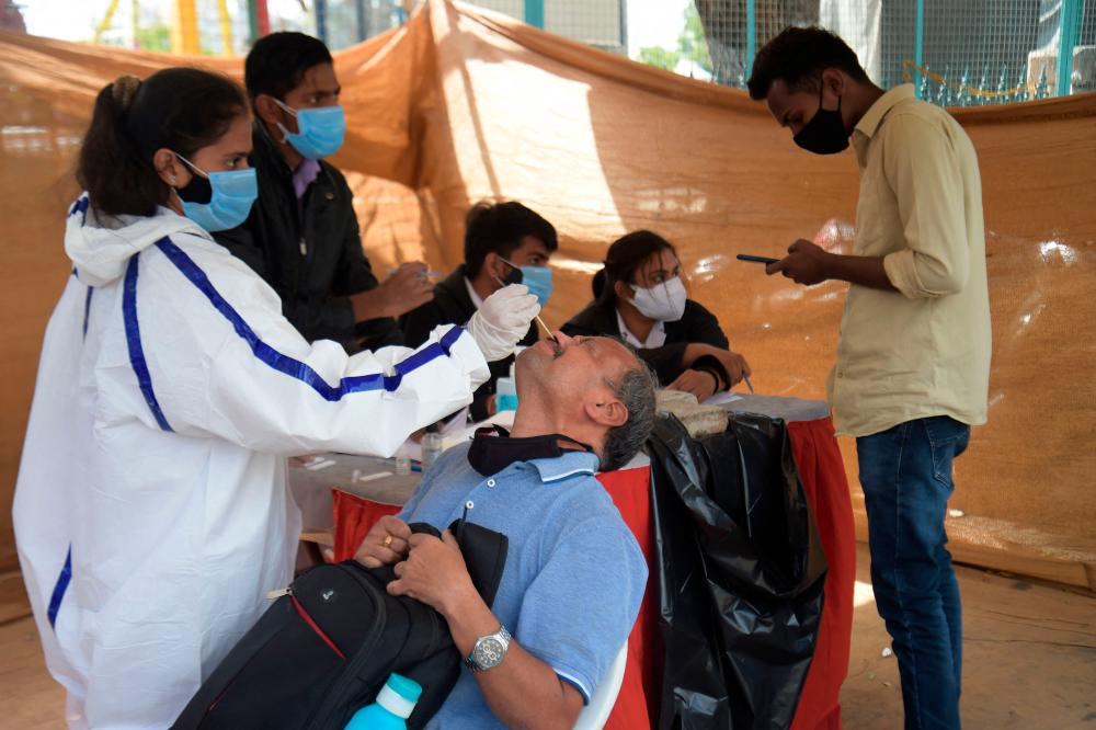A Health worker takes a nasal swab from a man to test for the Covid 19 coronavirus under a makeshift tent in Ahmedabad on January 22, 2022. AFPPIX