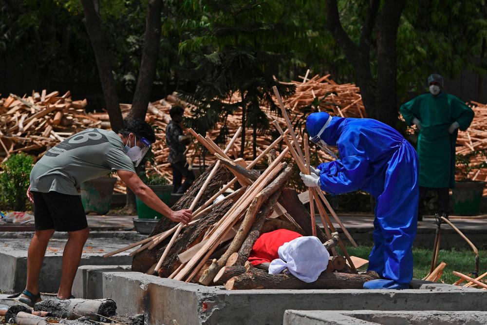 Family members prepare to cremate the body of a victim who died of the Covid-19 coronavirus at a cremation ground in New Delhi on May 4, 2021, as India’s total Covid caseload soared past 20 million. -