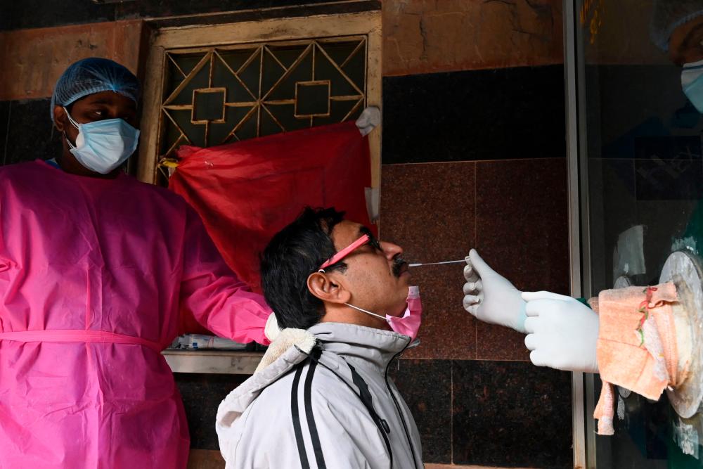 A health worker collects a swab sample from a man to test for the Covid-19 coronavirus at a government hospital in Kolkata on January 18, 2022. AFPPIX