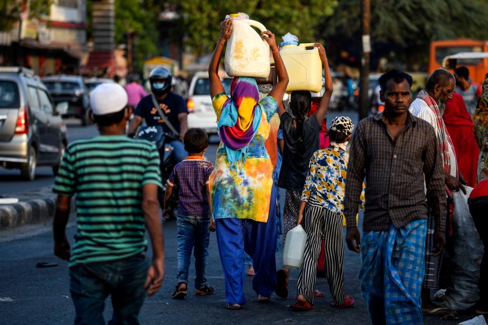 In this photograph taken on May 20, 2020, residents leave after they filled cans from a water distribution tanker as the government eases a nationwide lockdown imposed as a preventive measure against the Covid-19 coronavirus in New Delhi. — AFP