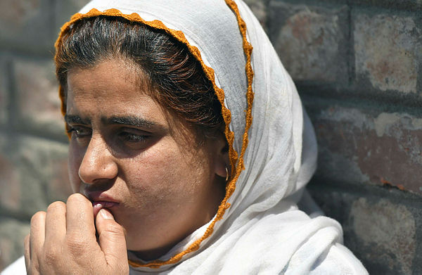 An Indian Kashmiri woman waits outside a police station after her relative was detained during night raids in Srinagar on Aug 20. — AFP