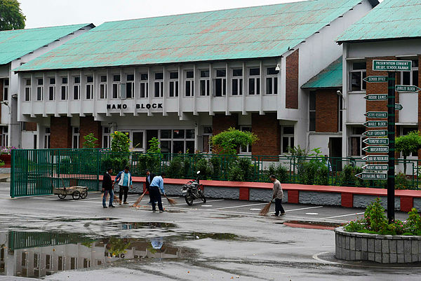 Workers clean the campus of a closed school in Srinagar on August 19, 2019. — AFP