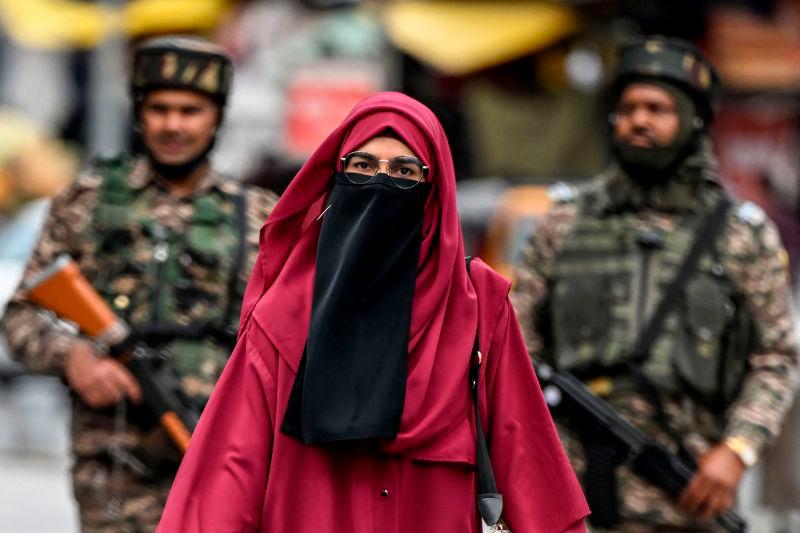 A Kashmiri woman walks at a marketplace as Indian paramilitary soldiers stand guard in Srinagar on May 3, 2025. AFPpix